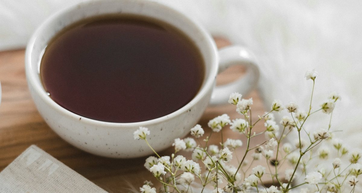 白いカップに入った紅茶と、白い小さな花